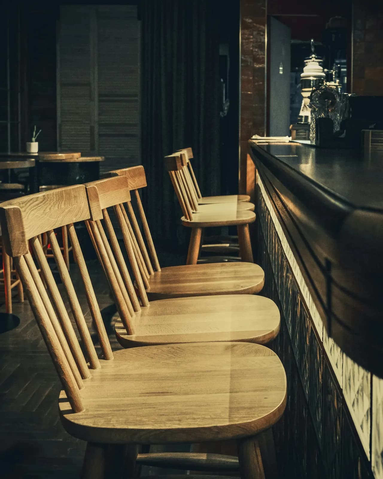 Empty wooden bar stools along a dark counter